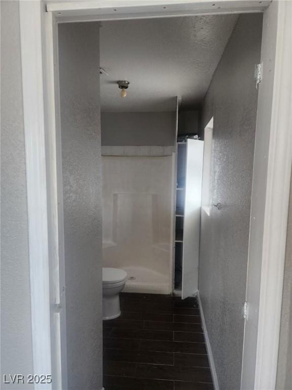 781 Buol Rd, Pahrump, NV 89048 - bathroom with a textured wall, toilet, baseboards, a shower, and wood finished floors