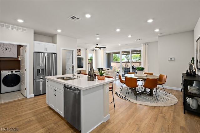 4180 E Brusca Way, Pahrump, NV 89061 - kitchen with washer / clothes dryer, a sink, appliances with stainless steel finishes, white cabinets, and an island with sink