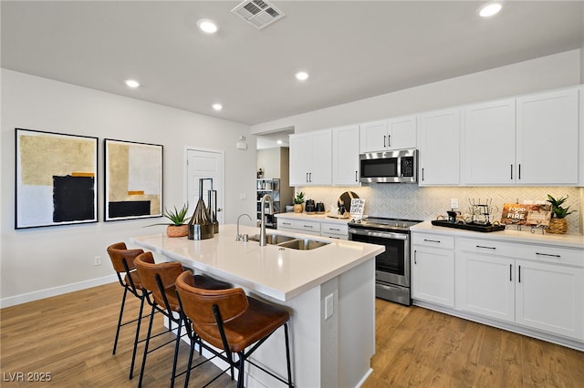 4180 E Brusca Way, Pahrump, NV 89061 - kitchen with appliances with stainless steel finishes, a sink, light wood-style flooring, tasteful backsplash, and recessed lighting