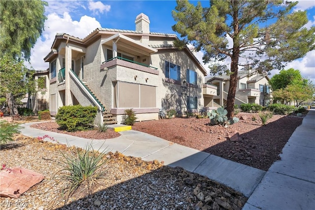 5710 E Tropicana Ave Unit 2152, Las Vegas, NV 89122 - view of front facade featuring a chimney, stucco siding, stairway, and a tiled roof