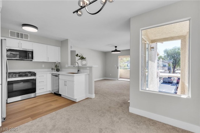5710 E Tropicana Ave Unit 2152, Las Vegas, NV 89122 - kitchen with appliances with stainless steel finishes, light colored carpet, a peninsula, a sink, and white cabinets