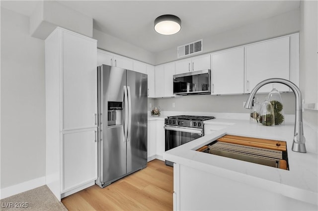 5710 E Tropicana Ave Unit 2152, Las Vegas, NV 89122 - kitchen featuring stainless steel appliances, a sink, white cabinets, light countertops, and light wood finished floors