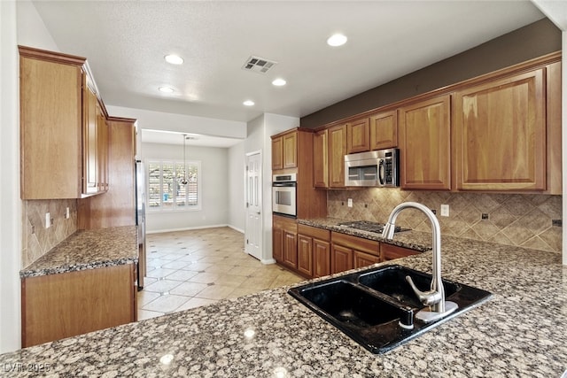11177 Twilight Times Ct, Las Vegas, NV 89135 - kitchen featuring stainless steel appliances, brown cabinetry, dark stone counters, tasteful backsplash, and recessed lighting