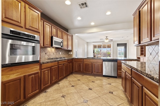 11177 Twilight Times Ct, Las Vegas, NV 89135 - kitchen featuring appliances with stainless steel finishes, recessed lighting, tasteful backsplash, brown cabinetry, and a ceiling fan