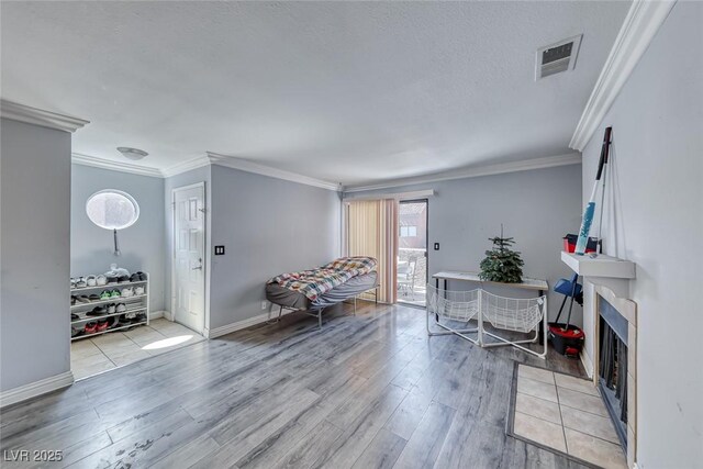 4050 Pacific Harbors Dr Unit 245, Las Vegas, NV 89121 - sitting room with light wood-type flooring, crown molding, baseboards, a fireplace, and a textured ceiling