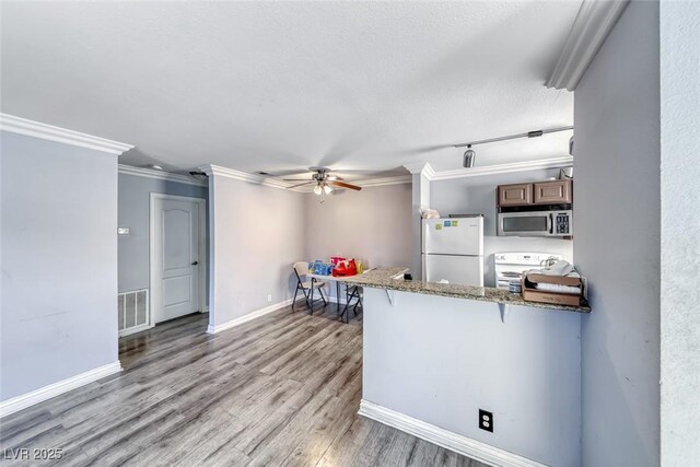 4050 Pacific Harbors Dr Unit 245, Las Vegas, NV 89121 - kitchen featuring white appliances, a ceiling fan, ornamental molding, light wood-style flooring, and a breakfast bar area