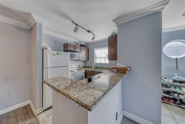4050 Pacific Harbors Dr Unit 245, Las Vegas, NV 89121 - kitchen with white appliances, crown molding, a sink, a peninsula, and light stone counters