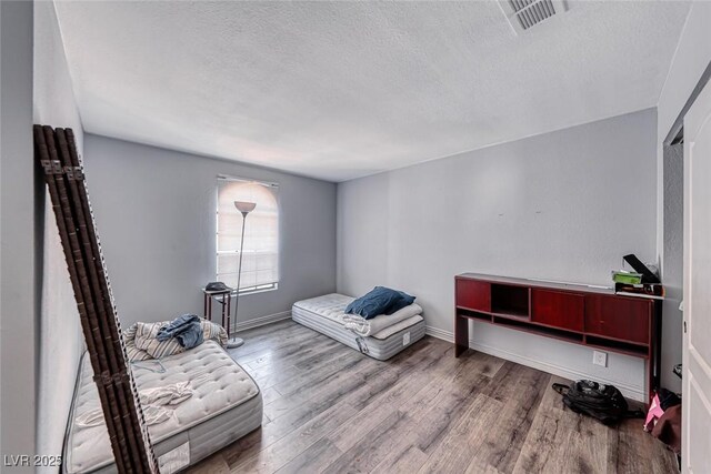 4050 Pacific Harbors Dr Unit 245, Las Vegas, NV 89121 - bedroom featuring a textured ceiling, wood finished floors, and baseboards
