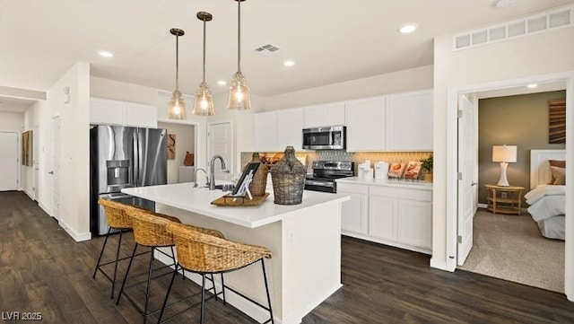 4200 E Brusca Way, Pahrump, NV 89061 - kitchen featuring appliances with stainless steel finishes, decorative backsplash, a kitchen breakfast bar, dark wood-style flooring, and a center island with sink