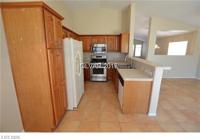 7518 Luna Del Rey St, Las Vegas, NV 89123 - kitchen featuring appliances with stainless steel finishes, light tile patterned flooring, tile counters, a sink, and vaulted ceiling