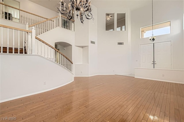 10241 Regents Cross Pl, Las Vegas, NV 89144 - unfurnished living room with a towering ceiling, a chandelier, stairs, wood finished floors, and baseboards