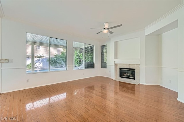 10241 Regents Cross Pl, Las Vegas, NV 89144 - unfurnished living room featuring crown molding, ceiling fan, wood finished floors, a tiled fireplace, and baseboards