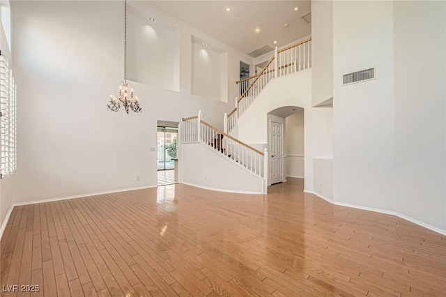 10241 Regents Cross Pl, Las Vegas, NV 89144 - unfurnished living room with a high ceiling, arched walkways, baseboards, a chandelier, and stairway