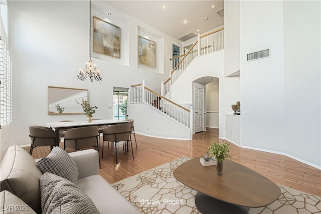 10241 Regents Cross Pl, Las Vegas, NV 89144 - living area featuring a high ceiling, arched walkways, stairway, a chandelier, and wood finished floors