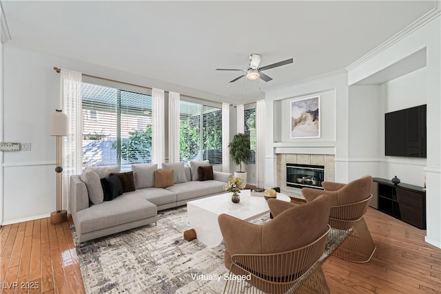 10241 Regents Cross Pl, Las Vegas, NV 89144 - living area with ceiling fan, light wood-style floors, a tiled fireplace, crown molding, and baseboards