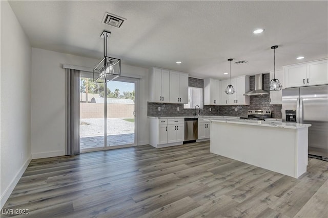 1901 Farnam Pl, Las Vegas, NV 89102 - kitchen featuring appliances with stainless steel finishes, wall chimney range hood, tasteful backsplash, light wood finished floors, and white cabinets