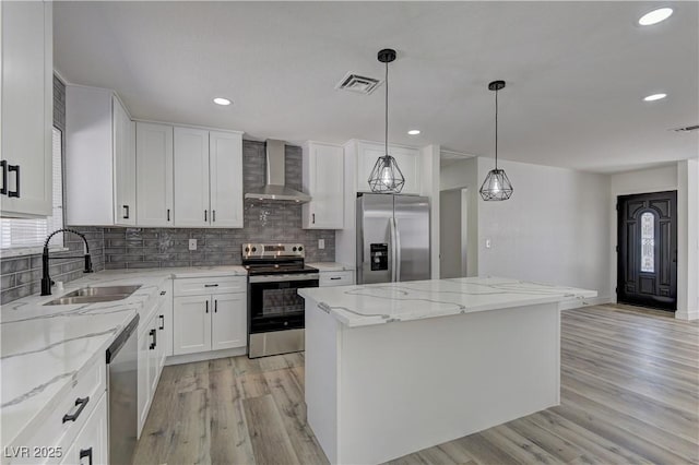 1901 Farnam Pl, Las Vegas, NV 89102 - kitchen featuring stainless steel appliances, wall chimney exhaust hood, a sink, a kitchen island, and light wood finished floors