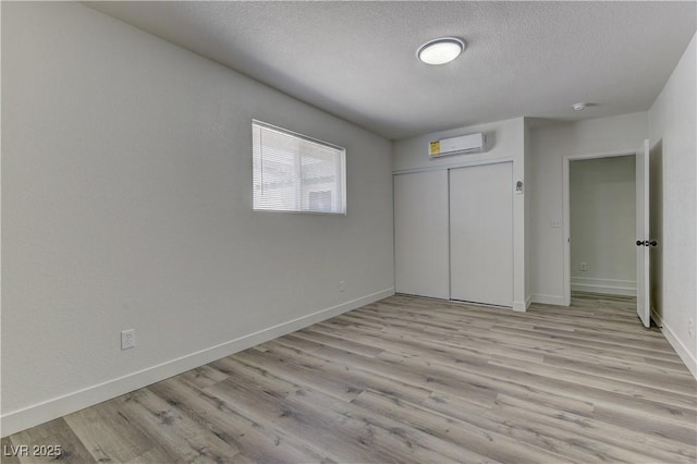 1901 Farnam Pl, Las Vegas, NV 89102 - unfurnished bedroom featuring a textured ceiling, wood finished floors, baseboards, a wall mounted AC, and a closet