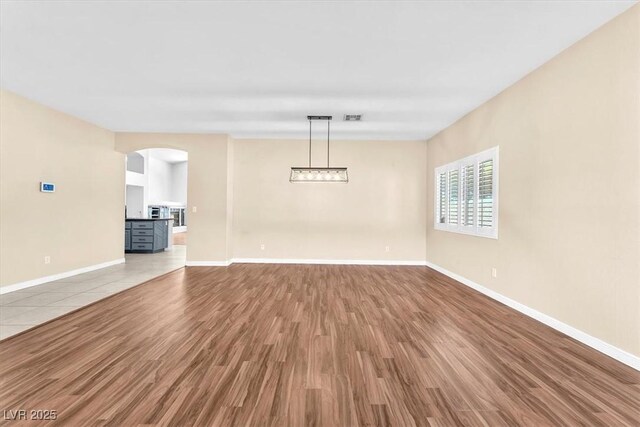 1088 Casady Hollow Ave, Henderson, NV 89012 - unfurnished living room featuring wood finished floors, baseboards, and arched walkways