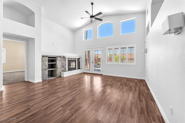 1088 Casady Hollow Ave, Henderson, NV 89012 - unfurnished living room featuring a ceiling fan, baseboards, wood finished floors, high vaulted ceiling, and a glass covered fireplace