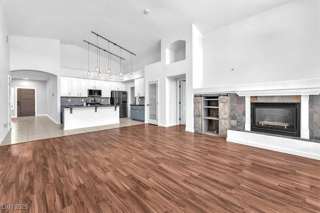 1088 Casady Hollow Ave, Henderson, NV 89012 - unfurnished living room with high vaulted ceiling, wood finished floors, a glass covered fireplace, and baseboards