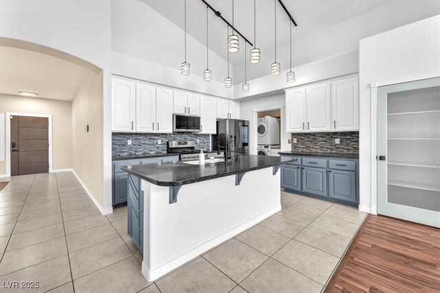 1088 Casady Hollow Ave, Henderson, NV 89012 - kitchen with stacked washer / drying machine, appliances with stainless steel finishes, a towering ceiling, light tile patterned floors, and arched walkways