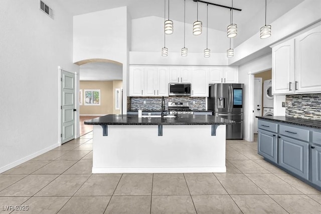 1088 Casady Hollow Ave, Henderson, NV 89012 - kitchen with stainless steel appliances, stacked washer and clothes dryer, arched walkways, a breakfast bar, and a sink