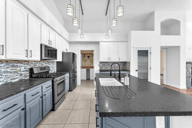 1088 Casady Hollow Ave, Henderson, NV 89012 - kitchen with stainless steel appliances, a sink, a kitchen island with sink, white cabinets, and tasteful backsplash