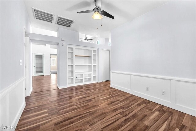 1088 Casady Hollow Ave, Henderson, NV 89012 - unfurnished room featuring ceiling fan, built in shelves, dark wood-type flooring, a decorative wall, and a wainscoted wall