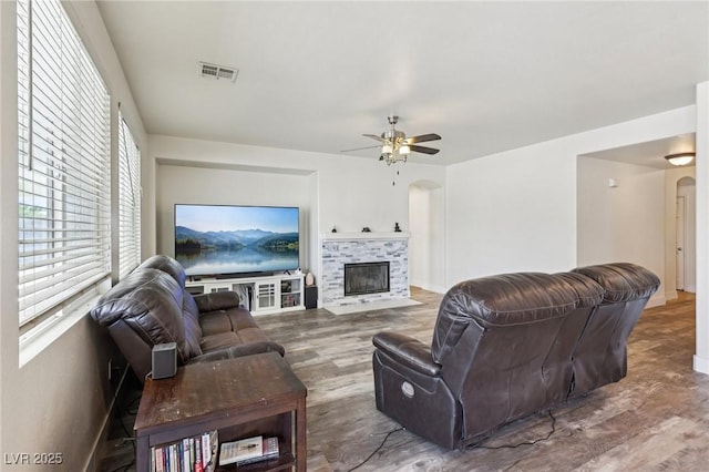 564 Lampshire Ln, Pahrump, NV 89060 - living room featuring arched walkways, a fireplace with flush hearth, ceiling fan, and wood finished floors