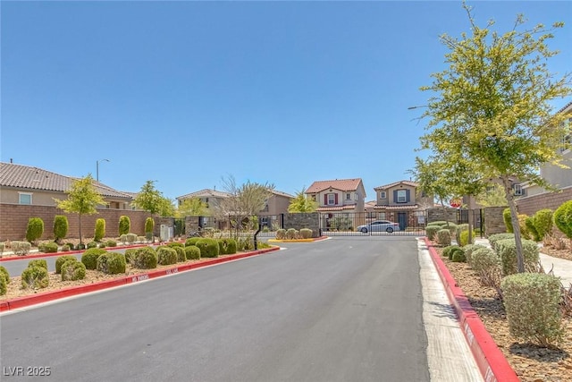 1130 Blissful Plains Ave, North Las Vegas, NV 89086 - view of asphalt road featuring a residential view, a gate, curbs, street lights, and a gated entry