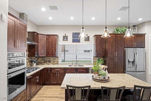 219 Windsong Dr, Henderson, NV 89074 - kitchen featuring a sink, appliances with stainless steel finishes, a kitchen breakfast bar, light wood finished floors, and decorative backsplash