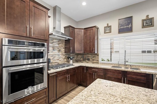 219 Windsong Dr, Henderson, NV 89074 - kitchen with wall chimney exhaust hood, stainless steel appliances, a sink, light wood finished floors, and light stone countertops