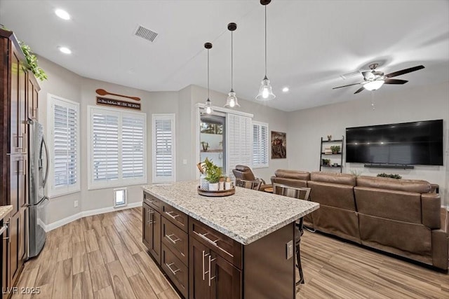 219 Windsong Dr, Henderson, NV 89074 - kitchen featuring a breakfast bar area, stainless steel fridge with ice dispenser, light wood-style floors, a ceiling fan, and dark brown cabinetry