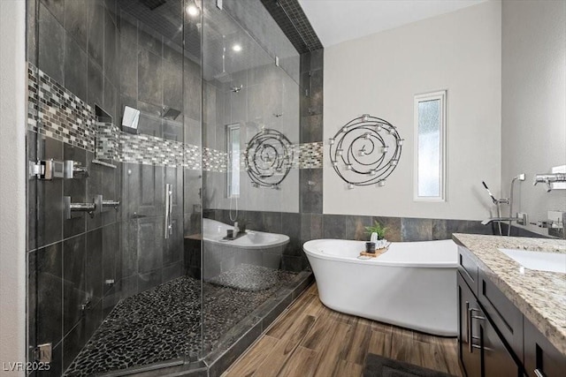 219 Windsong Dr, Henderson, NV 89074 - bathroom with tile walls, a shower stall, a freestanding tub, vanity, and wood finished floors