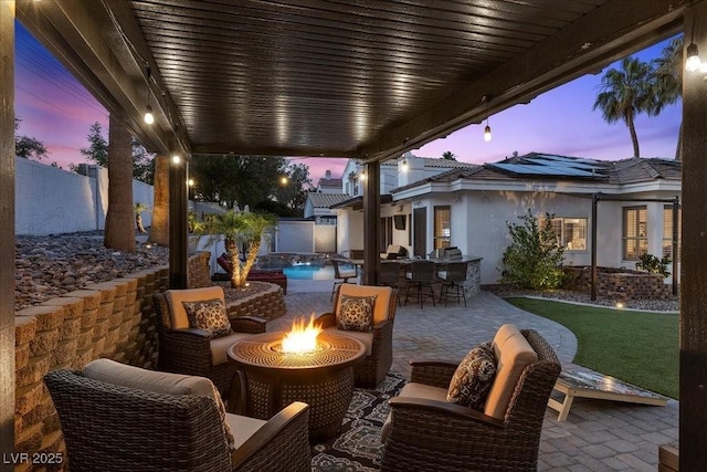 219 Windsong Dr, Henderson, NV 89074 - patio terrace at dusk with a patio, an outdoor living space with a fire pit, and a fenced backyard