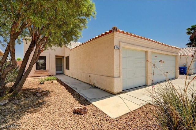 1902 Panther Pl, North Las Vegas, NV 89031 - view of side of property featuring a tiled roof, a garage, stucco siding, and driveway