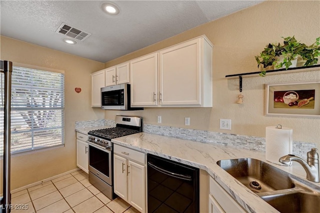 1902 Panther Pl, North Las Vegas, NV 89031 - kitchen with stainless steel appliances, a sink, white cabinetry, light tile patterned floors, and a textured ceiling