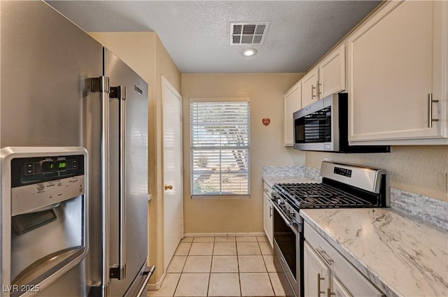 1902 Panther Pl, North Las Vegas, NV 89031 - kitchen with stainless steel appliances, white cabinets, light stone countertops, a textured ceiling, and baseboards