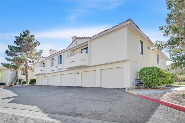 2633 S Durango Dr Unit 204, Las Vegas, NV 89117 - view of home's exterior featuring stucco siding, an attached garage, asphalt driveway, and a tile roof