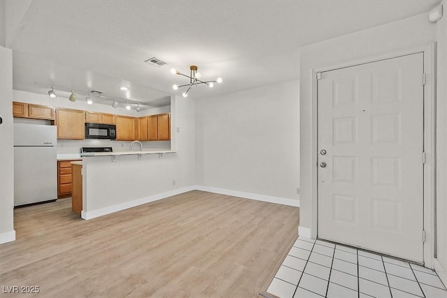2633 S Durango Dr Unit 204, Las Vegas, NV 89117 - kitchen featuring black microwave, freestanding refrigerator, stove, light countertops, and light wood finished floors