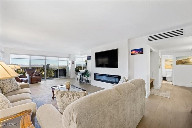 3111 Bel Air Dr Unit 7F, Las Vegas, NV 89109 - living area featuring a glass covered fireplace, light wood-type flooring, and baseboards