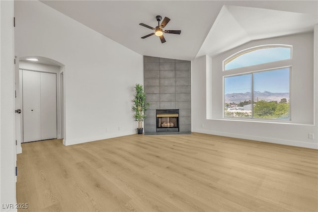4800 Grey Wolf Ln Unit 202, Las Vegas, NV 89149 - unfurnished living room featuring vaulted ceiling, a ceiling fan, light wood-type flooring, a fireplace, and arched walkways