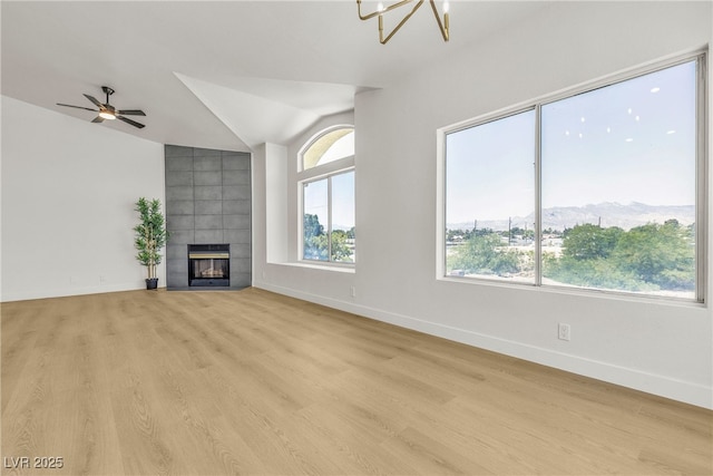 4800 Grey Wolf Ln Unit 202, Las Vegas, NV 89149 - unfurnished living room with lofted ceiling, a tile fireplace, light wood finished floors, a ceiling fan, and a chandelier