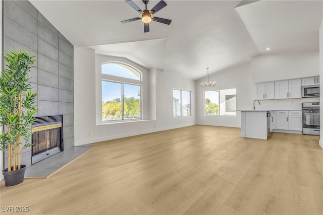 4800 Grey Wolf Ln Unit 202, Las Vegas, NV 89149 - unfurnished living room with a tiled fireplace, a chandelier, light wood-style flooring, a ceiling fan, and high vaulted ceiling