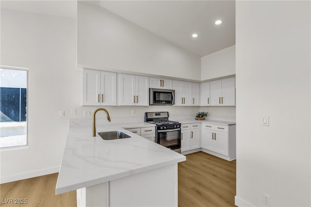 4800 Grey Wolf Ln Unit 202, Las Vegas, NV 89149 - kitchen with appliances with stainless steel finishes, a peninsula, high vaulted ceiling, light stone counters, and white cabinets