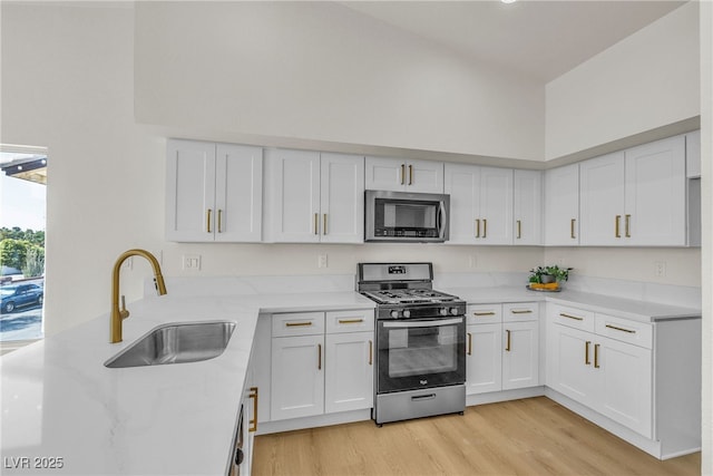 4800 Grey Wolf Ln Unit 202, Las Vegas, NV 89149 - kitchen featuring stainless steel appliances, white cabinets, light wood finished floors, a high ceiling, and a peninsula