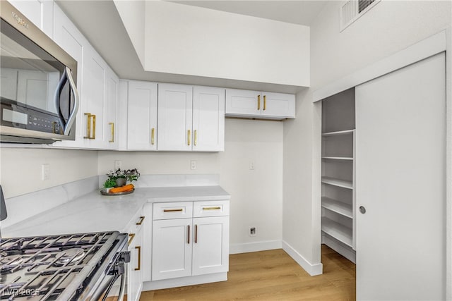 4800 Grey Wolf Ln Unit 202, Las Vegas, NV 89149 - kitchen featuring stainless steel microwave, white cabinets, light wood-style flooring, gas range, and light countertops
