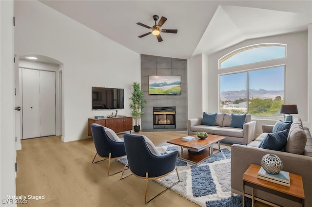 4800 Grey Wolf Ln Unit 202, Las Vegas, NV 89149 - living room with a ceiling fan, high vaulted ceiling, light wood-type flooring, arched walkways, and a tiled fireplace