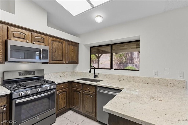 6997 Ray Charles Ln, Las Vegas, NV 89119 - kitchen featuring stainless steel appliances, a sink, light stone countertops, light tile patterned floors, and dark brown cabinets